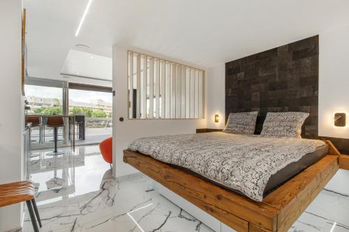 een slaapkamer met een groot bed met een houten hoofdeinde bij Unik Heliopolis naturiste in Cap d'Agde