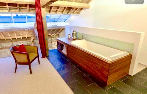 ein Bad mit einer Badewanne und einem Stuhl in einem Zimmer in der Unterkunft Royal William Yard Apartments - Large and Luxurious with Free Parking in Plymouth