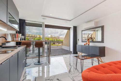 une cuisine avec un canapé orange, une table et des chaises dans l'établissement Unik Heliopolis naturiste, au Cap d'Agde