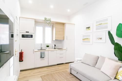 a white living room with a couch and a kitchen at Acogedor y conveniente piso reformado en Salamanca in Madrid
