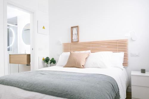 - une chambre avec un grand lit et une tête de lit en bois dans l'établissement Acogedor y conveniente piso reformado en Salamanca, à Madrid