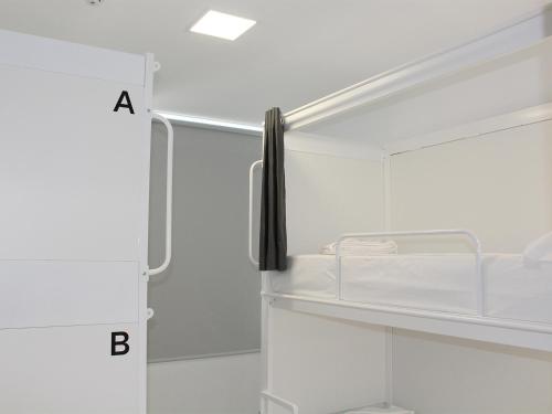 a bathroom with a white refrigerator with a shelf at Dunas Hostel & Guesthouse in Alvor