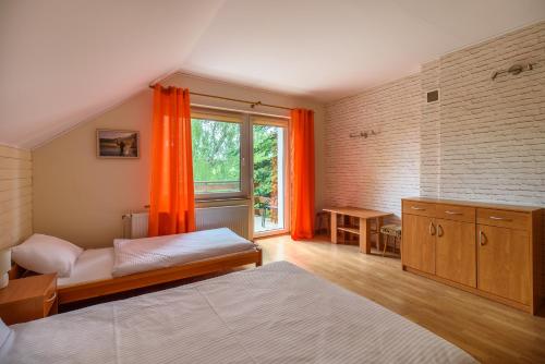 ビエレにあるKaszubski Senのベッドルーム1室(ベッド2台付)、窓(オレンジ色のカーテン付)
