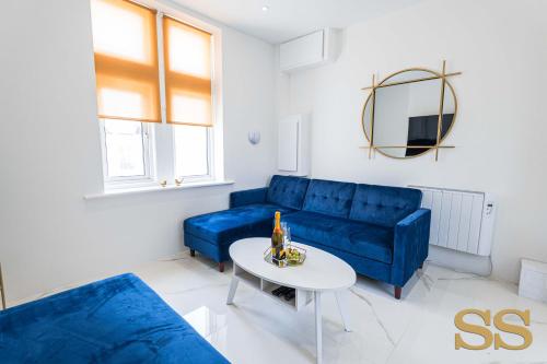 ein Wohnzimmer mit einem blauen Sofa und einem Tisch in der Unterkunft Blue Lagoon - 1 MINUTE FROM 02 ACADEMY - FREE PARKING - 5 MINUTES FROM THE BEACH - FAST WI-FI - SMART TV in Bournemouth