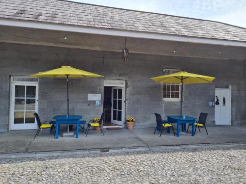 two tables and chairs with yellow umbrellas in front of a building at Loughcrew Courtyard House in Oldcastle