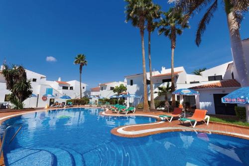 une grande piscine avec des palmiers et des bâtiments blancs dans l'établissement Puerto Caleta, à Caleta de Fuste
