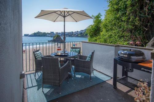 a patio with a table and chairs and an umbrella at The Sand Castle - 2 Bedroom Apartment - Tenby in Tenby