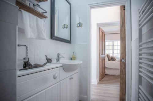 a white bathroom with a sink and a mirror at The Sand Castle - 2 Bedroom Apartment - Tenby in Tenby