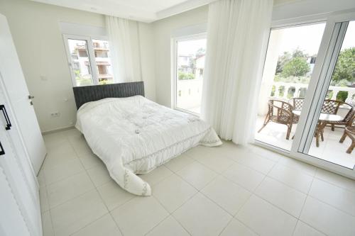 Habitación blanca con cama y balcón. en Aguarius Villas, en Side