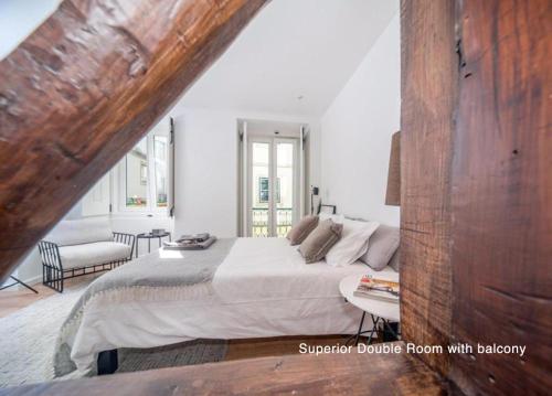 a white bedroom with a bed and a chair at Bairro House Lisbon Charming Suites in Lisbon