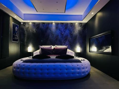 een slaapkamer met een groot bed en een blauw plafond bij La Nuit Coquine - Suite avec Jacuzzi - Evasion in Le Mans