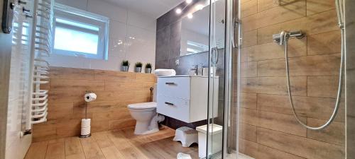a bathroom with a toilet and a glass shower at Pokoje i Apartamenty na Szkolnej in Zator