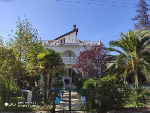 una gran casa blanca con palmeras delante en Tatil Evi Triblex, en Atakum