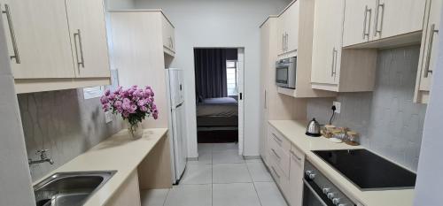 una cocina con armarios blancos y un jarrón de flores en la encimera en Luxury Cottage - Malmesbury, en Malmesbury