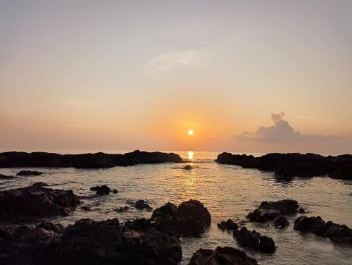 a sunset over the ocean with rocks in the water at Adhvasaha Beach Spa Resort in Port Blair