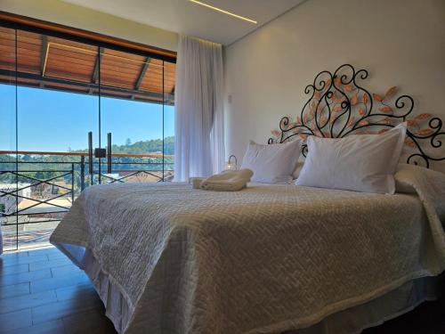 a bedroom with a large bed with a large window at Hotel Villa Greenberg in Monte Verde