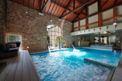 uma grande piscina num quarto com uma parede de tijolos em The Devonshire Arms Hotel & Spa - Skipton em Bolton Abbey