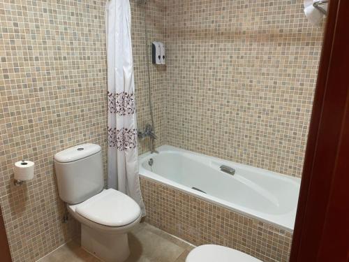 a bathroom with a toilet and a bath tub with at Vall Fosca Apartment "Majue" in Torre de Capdella