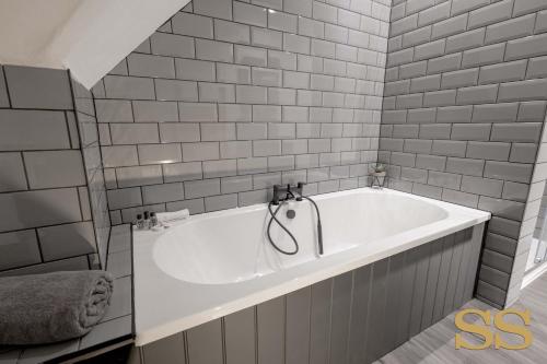 baño con bañera blanca y azulejos grises en The Hideaway - 1 MINUTE FROM 02 ACADEMY - FREE PARKING - 5 MINUTES FROM THE BEACH - FAST WI-FI - SMART TV, en Bournemouth