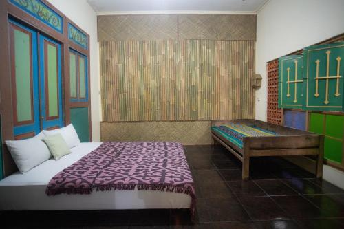 1 dormitorio con cama y banco. en Rumah Kalpataru, en Yogyakarta