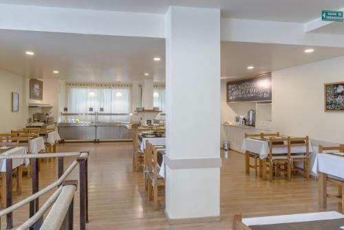 un restaurante con paredes blancas y mesas y sillas de madera en Soft Bariloche Hotel, en San Carlos de Bariloche