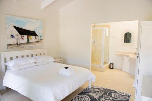 ein Schlafzimmer mit einem weißen Bett und einem Gemälde an der Wand in der Unterkunft Osler Place Self-Catering in Stilbaai