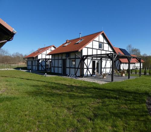 two large white and black buildings with a grass field at Domki Trzy - 2 in Smołdziński Las
