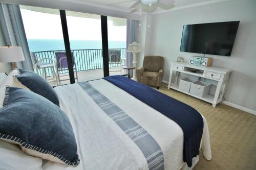 a bedroom with a bed with a television and a balcony at Daytona Ashley Penthouse 4 in Daytona Beach Shores