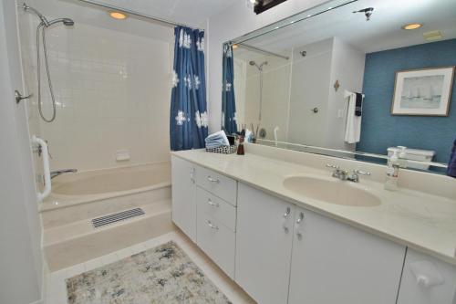 a bathroom with a sink and a tub and a mirror at Daytona Ashley Penthouse 4 in Daytona Beach Shores