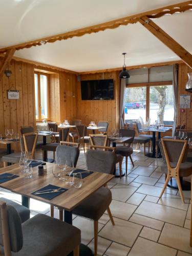 a dining room with tables and chairs and windows at Hôtel Restaurant des Lacs in Chaux-des-Crotenay