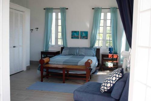 ein Schlafzimmer mit einem Bett, einem Sofa und Fenstern in der Unterkunft 2 Bed 2bath Cottage Pickleball Court Pool in Providenciales