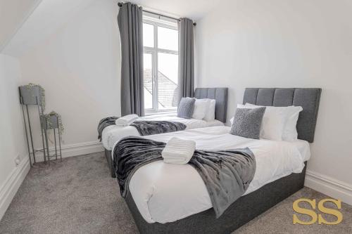 two twin beds in a room with a window at Pearl Penthouse - 1 MINUTE FROM 02 ACADEMY - FREE PARKING - 5 MINUTES FROM THE BEACH - FAST WI-FI - SMART TV in Bournemouth