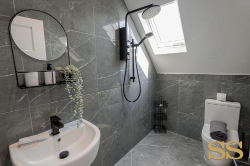 W łazience znajduje się umywalka, lustro i toaleta. w obiekcie Pearl Penthouse - 1 MINUTE FROM 02 ACADEMY - FREE PARKING - 5 MINUTES FROM THE BEACH - FAST WI-FI - SMART TV w Bournemouth