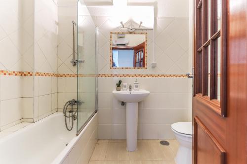 a bathroom with a sink and a toilet and a mirror at Vita Portucale ! Sandset Park View in Costa da Caparica