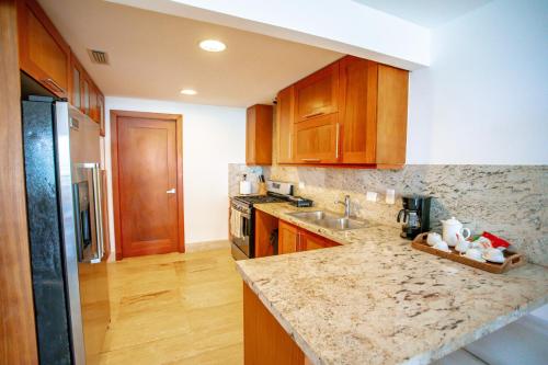a kitchen with wooden cabinets and a marble counter top at Xeliter Balcones del Atlantico - Las Terrenas in Las Terrenas