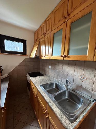 una cocina con fregadero de acero inoxidable y armarios de madera en BovecApartmentA en Bovec