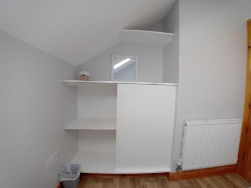 a room with a white wall and a shelf at The Red Door Townhouse Apartment in Ardara