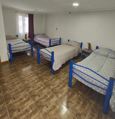 a room with three beds and a wooden floor at Alojamiento El Cóndor in Esquel