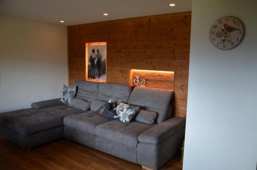 un sofá gris en una sala de estar con reloj en Ferienwohnung Mankei en Schönau am Königssee