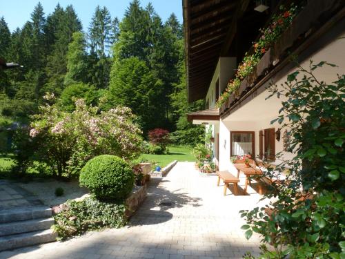 un patio de una casa con bancos y flores en Ferienwohnung Mankei en Schönau am Königssee