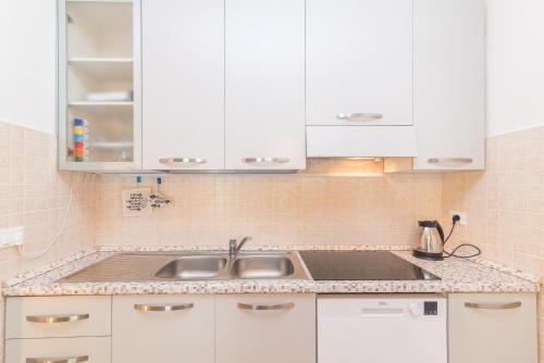 a kitchen with white cabinets and a sink at Loriana seaside home in Santa Teresa Gallura