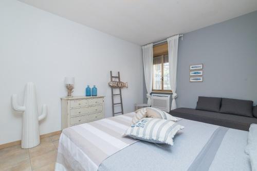 a white bedroom with a bed and a dresser at Loriana seaside home in Santa Teresa Gallura