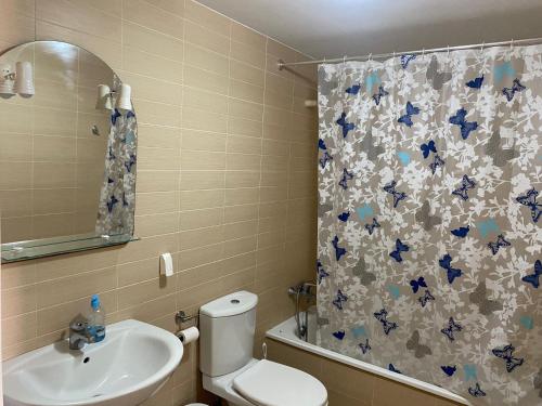 y baño con aseo, lavamanos y cortina de ducha. en Apartamento Portofino Golf & Puerto Almerimar, en Almerimar
