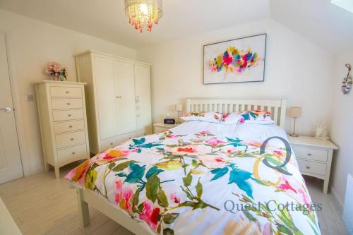 a bedroom with a large bed with a floral bedspread at 23 By The Sea - Modern Beach Apartment for 1 pet in Camber