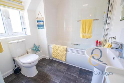 a bathroom with a toilet and a tub and a sink at 23 By The Sea - Modern Beach Apartment for 1 pet in Camber