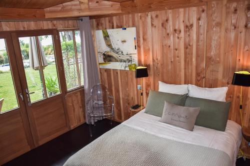 a bedroom with a bed with wooden walls and windows at La Maison Moutchic in Lacanau