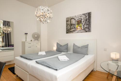 a white bedroom with a white bed and a table at Apartments an der Arena Leipzig in Leipzig