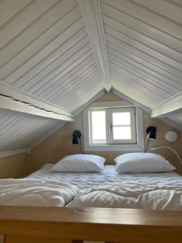 a bed with white sheets and a window in a room at Stuga i centrala Älvdalen in Älvdalen