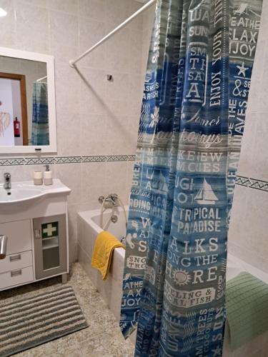 een badkamer met een douchegordijn, een wastafel en een bad bij Camarção Violante in Foz do Arelho