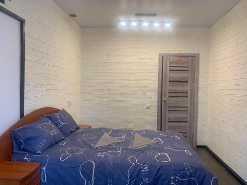 a bedroom with a bed with a blue comforter at Апартаменти на вул. Біла,5а in Rivne